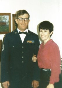 A man in uniform and a woman. Both standing arm in arm.