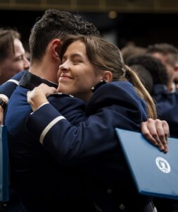 Graduates hugging with Diplomas and caps