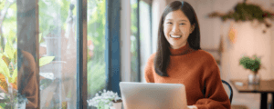 A woman smiles over her laptop